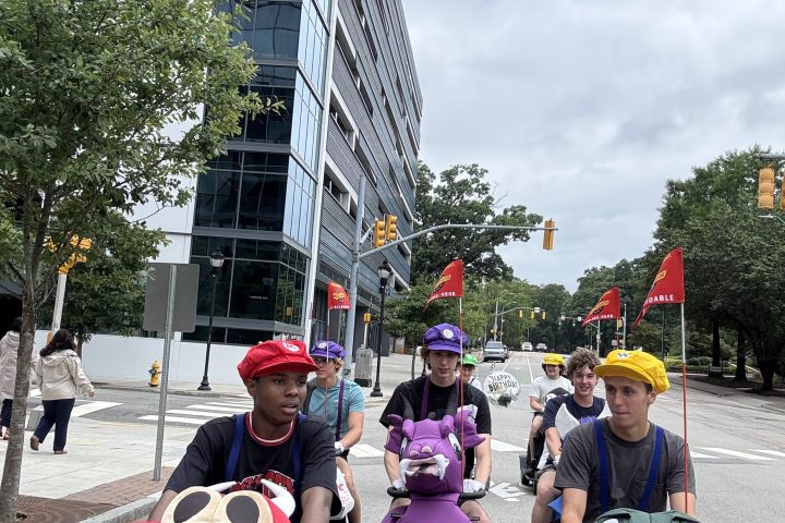 People in character costumes sitting on scooters in an urban area.