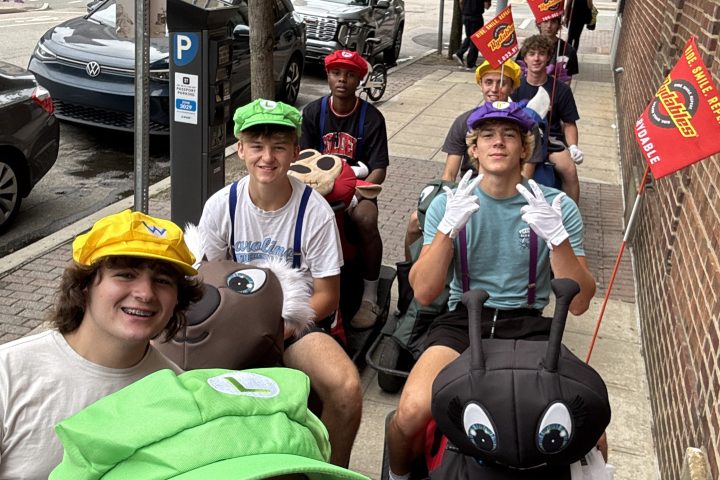 Group of people in colorful costumes posing on a sidewalk.