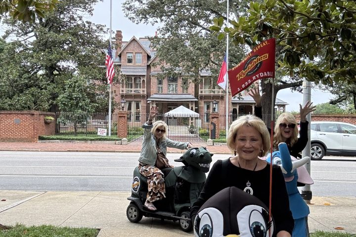 People in costumes posing on a sidewalk, with trees and buildings in the background.