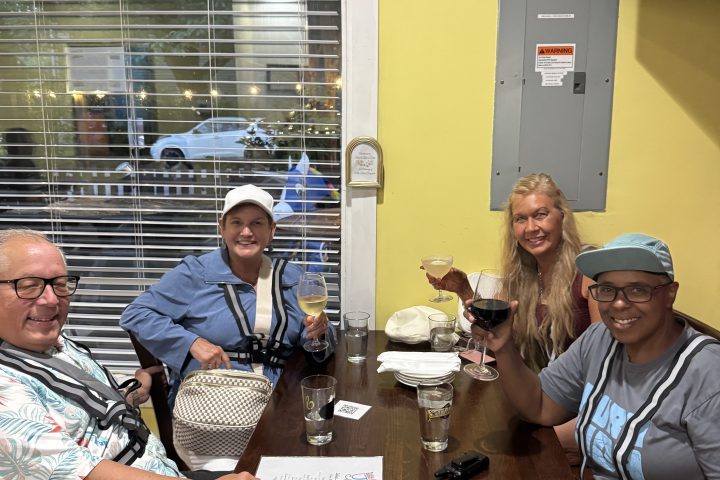 Four people sitting at a table in a restaurant, smiling at the camera.