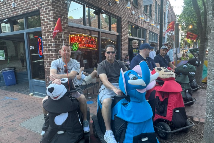 Group of adults riding animal scooters in front of a store.