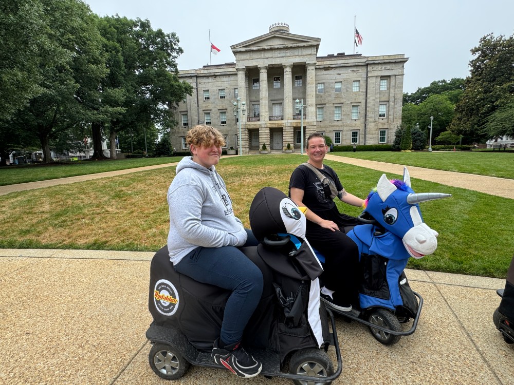 Two people on animal-themed scooters in front of a historic building.